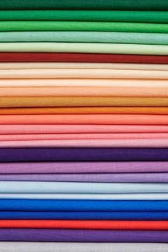 Stack of bright self-colored cotton fabrics as a background image Fotos de archivo