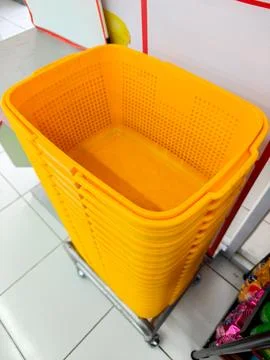 Stack of Bright Yellow Plastic Shopping Baskets on a Trolley Stockfoto's
