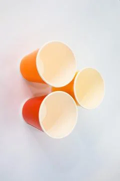 Stack of brightly colored paper cups against a clean, minimalist white back.. Stock Photos