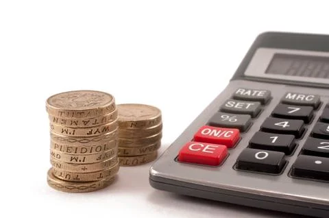 Stack of british pound coins next to a calculator Stock Photos