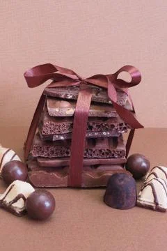 A stack of broken chocolate of different varieties tied with brown satin ribb Stock Photos
