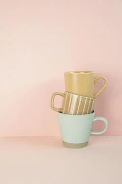 Stack of brown and mint blue mug cups on pink table. pink wall background Stock Photos