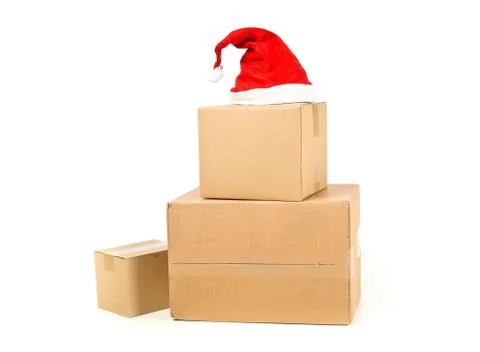 Stack of brown carton cardboard boxes with red santa hat over white backgroun 스톡 사진