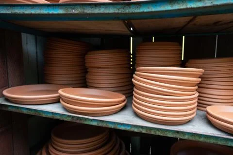 Stack of brown planter saucers on shelves at outdoor nursery Stock Photos