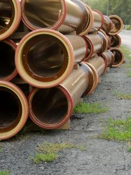 Stack of brown water pipes on the road. Stock Photos