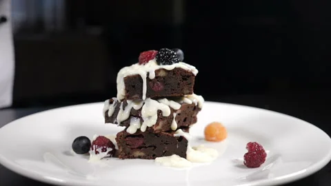 Stack of brownies dessert being decorated with berries on white plate. Falling Stock Footage 140557822