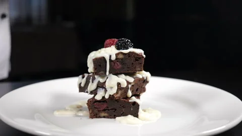 Stack of brownies dessert being decorated with berries on white plate. Falling Stock Footage 141515759