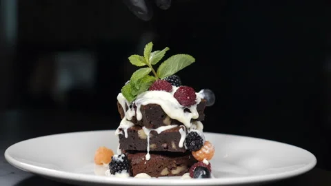 Stack of brownies dessert being decorated with berries on white plate. Falling Stock Footage 141515890