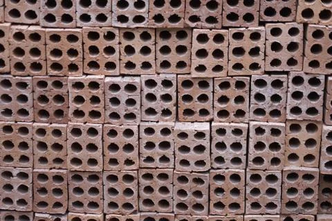 Stack of building bricks made of red clay with holes in handicraft production 写真素材