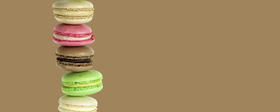 Stack of cake macarons on a chocolate brown background with copy space Stock Photos