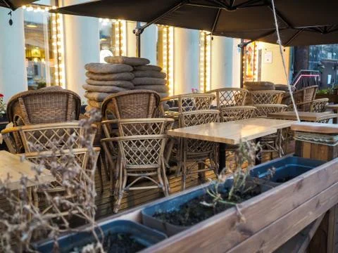 Stack of cane street chairs and tables on an autumn evening in the light of shop Stock Photos