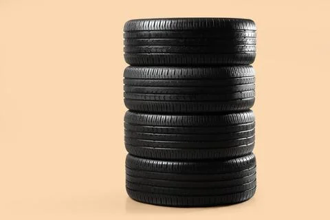 Stack of car tires on beige background Fotos de archivo