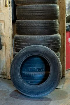 Stack of car tires in a workshop, one tire in foreground Stock Photos