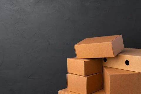 Stack of cardboard boxes against black background Stock Photos