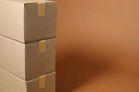 Stack of cardboard boxes on brown background, space for text Stock Photos