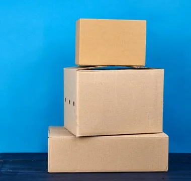 Stack of cardboard boxes of brown kraft paper on a blue wooden table Stock Photos