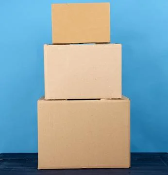 Stack of cardboard boxes of brown kraft paper on a blue wooden table Stock Photos