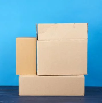 Stack of cardboard boxes of brown kraft paper on a blue wooden table Stock Photos
