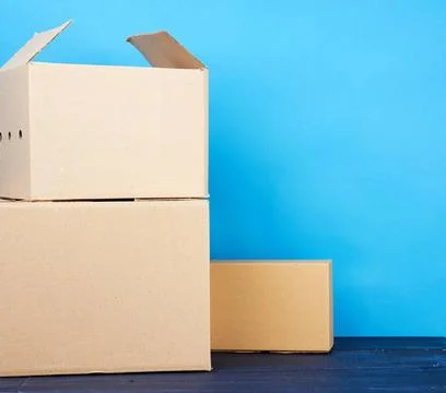 Stack of cardboard boxes of brown kraft paper on a blue wooden table stack... Stock Photos