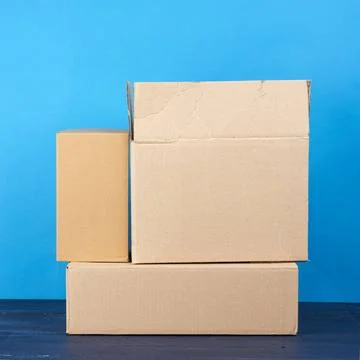 Stack of cardboard boxes of brown kraft paper on a blue wooden table stack... Stock Photos