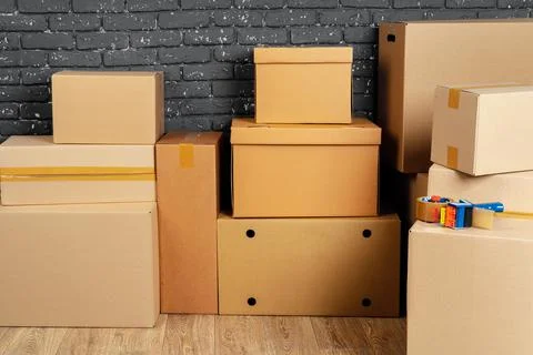 Stack of cardboard boxes in the empty room against black brick wall 写真素材