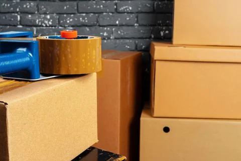 Stack of cardboard boxes in the empty room against black brick wall Stock Photos