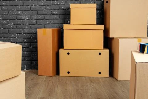 Stack of cardboard boxes in the empty room against black brick wall Foto stock