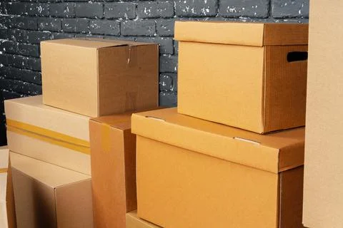 Stack of cardboard boxes in the empty room against black brick wall Stockfoto's