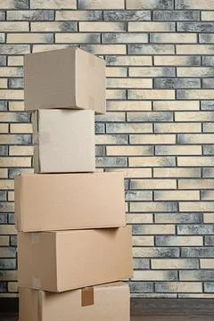 Stack of cardboard boxes near brick wall. Space for text Stock Photos