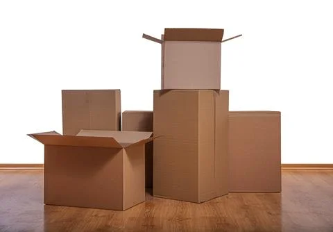 Stack of cardboard boxes on a wooden floor against a white background Stock Photos