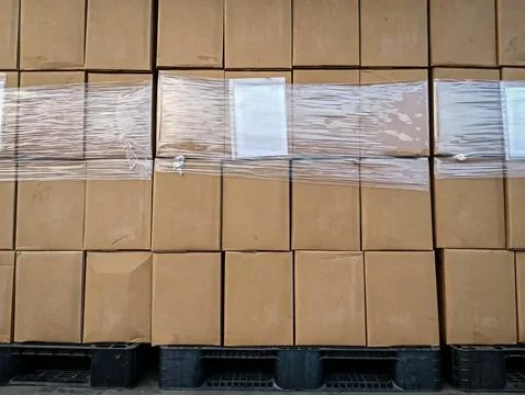 Stack of cardboard boxes wrapped in stretch film on black pallets Stock Photos