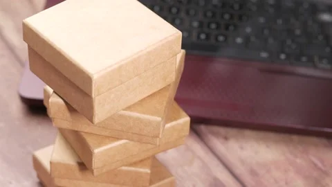 Stack of cardboard parcels and laptop on table Stockbeeldmateriaal 198680760