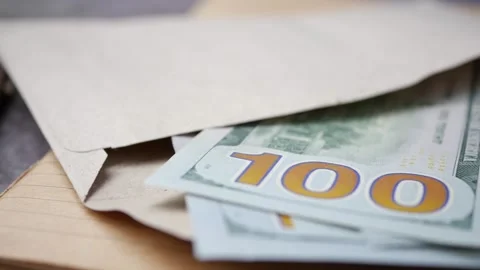 A stack of cash carefully placed inside an envelope rests on a wooden table Stock Footage 347696864