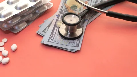 Stack of cash dollars , pills and stethoscope on pink background Stock Footage 128094167