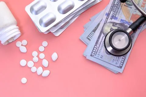 Stack of cash dollars , pills and stethoscope on pink background Stock Photos