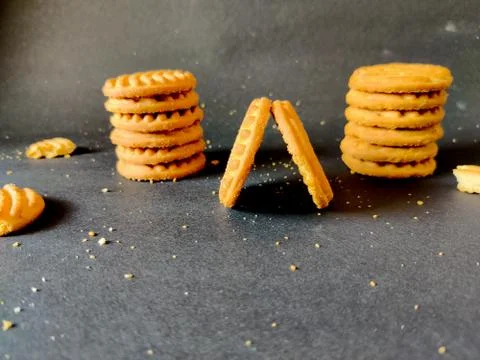 Stack of cashew cookies or biscuits and crushed cookies isolated on black bac Stock Photos