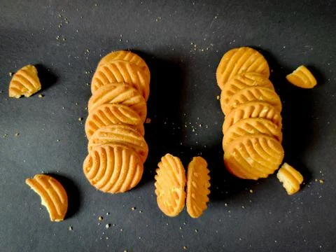 Stack of cashew cookies or biscuits and crushed cookies isolated on black bac Stock Photos