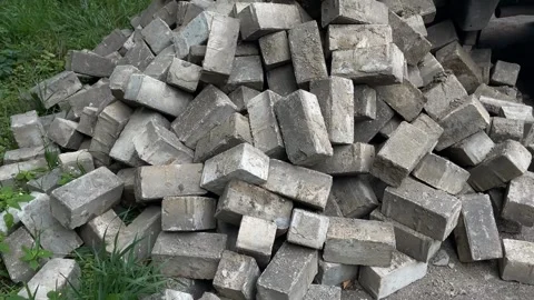Stack of cement bricks piled randomly outdoors near green grass background Stock Footage 344421595