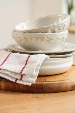 Stack of ceramic bowls and plates with kitchen towel on wooden board Stock Photos