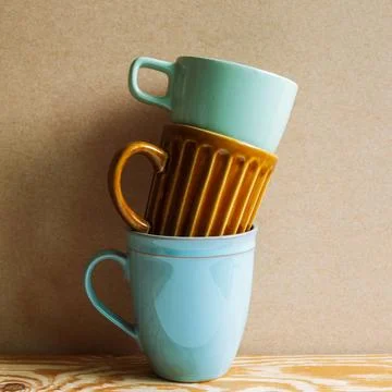 Stack of ceramic mug cups on wooden table with brown background Stack of c... Stock Photos