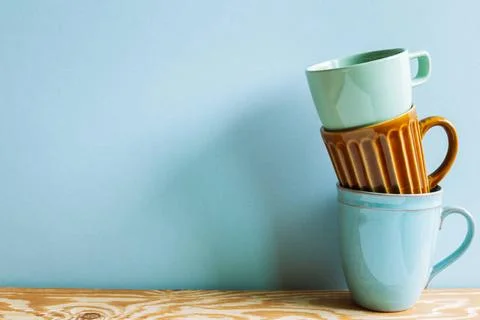 Stack of ceramic mug cups on wooden table with blue background Stack of ce... Stock Photos