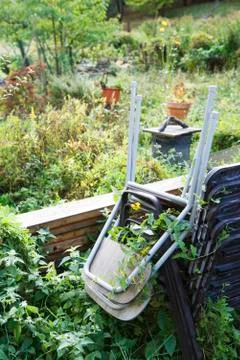 Stack of chairs in overgrown garden Stock Photos
