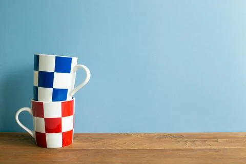 Stack of check pattern mug cup on wooden table. blue wall background Stock Photos