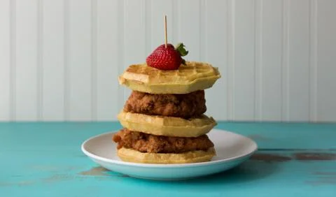 Stack of chicken and waffles with strawberry garnish. Fotos de archivo