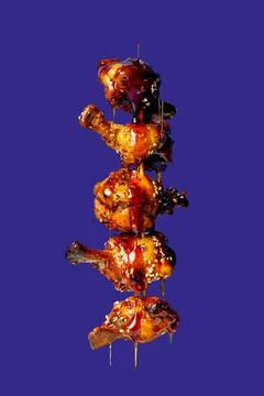 A stack of chicken wings with dripping sauce on a blue background. Poster wit Stock Photos