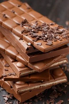Stack of chocolate and scattered chocolate chips on wooden background Stock Photos