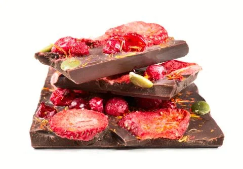 Stack of chocolate bar pieces with dried strawberries and cranberry on white Stock Photos