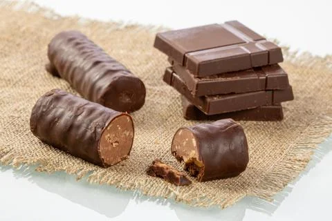 Stack of chocolate bars and cut chocolate candy on a burlap napkin Stock Photos