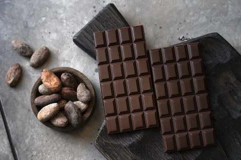 Stack of chocolate bars with cocoa beans. Flat lay composition with delicious Stock Photos