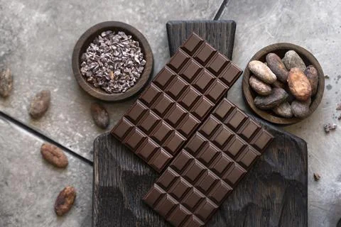Stack of chocolate bars with cocoa beans. Flat lay composition with delicious Foto stock